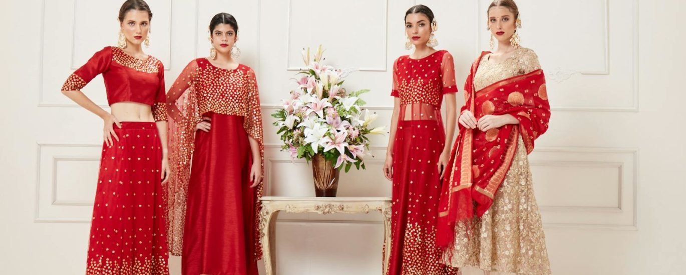 Four women showcasing luxurious Indian lehengas in a studio setting. Perfect blend of traditional elegance and modern style.