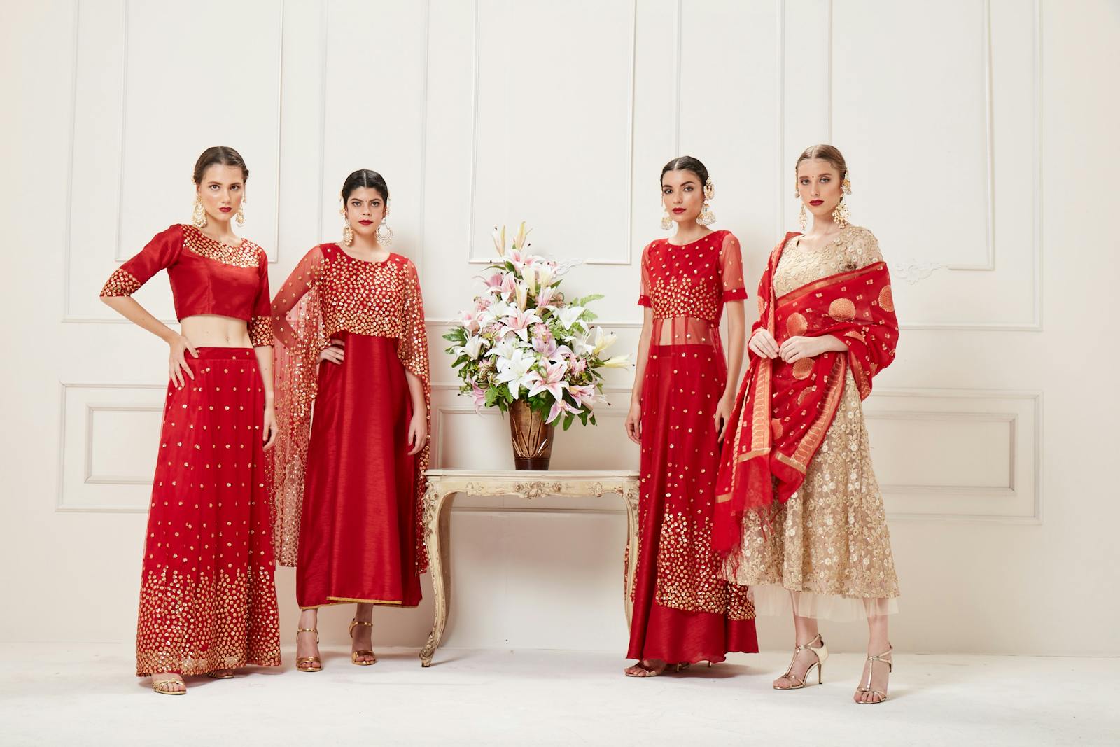 Four women showcasing luxurious Indian lehengas in a studio setting. Perfect blend of traditional elegance and modern style.