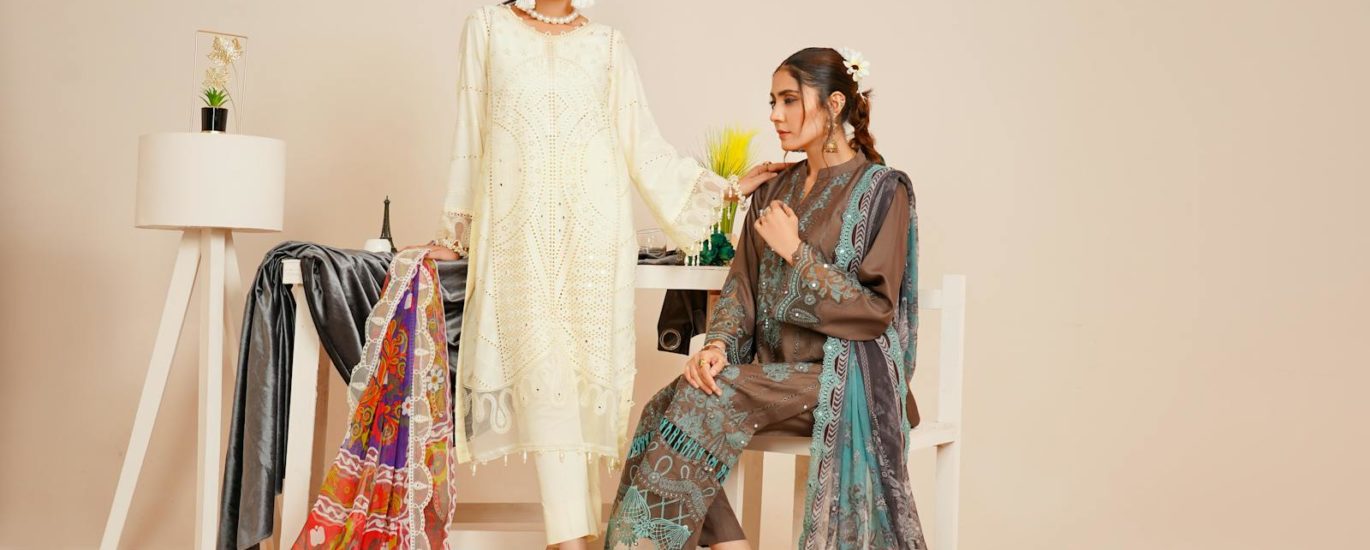 Two models in stylish Pakistani fashion attire captured in a studio setting.