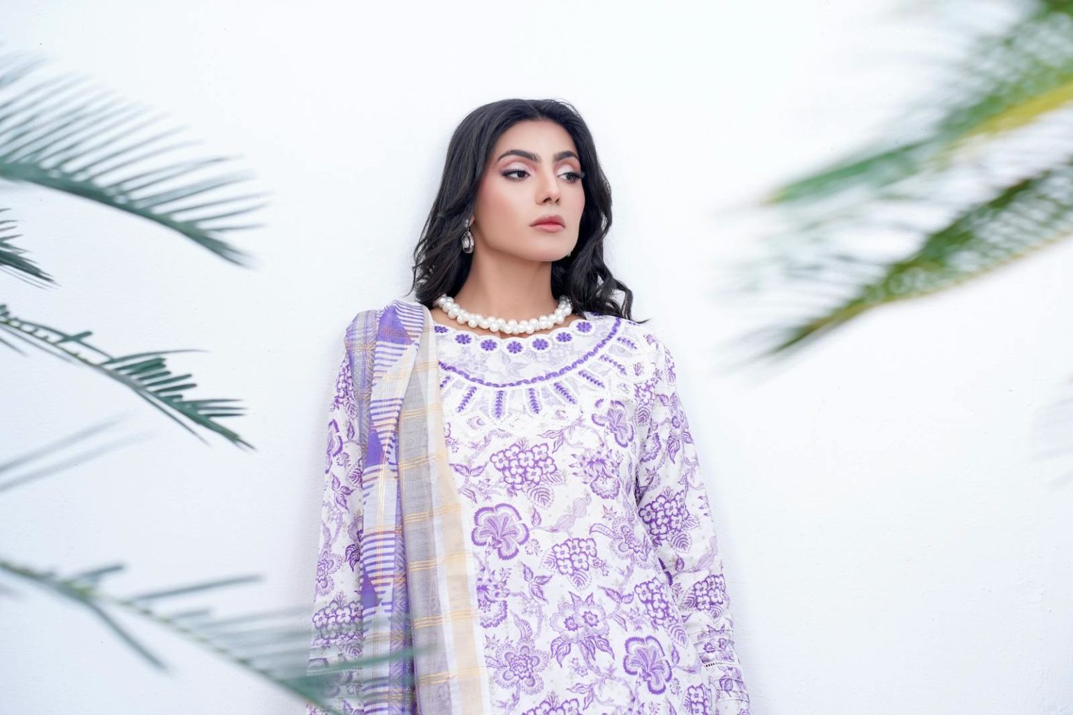 Portrait of a woman in purple and white floral shalwar kameez, outdoors.