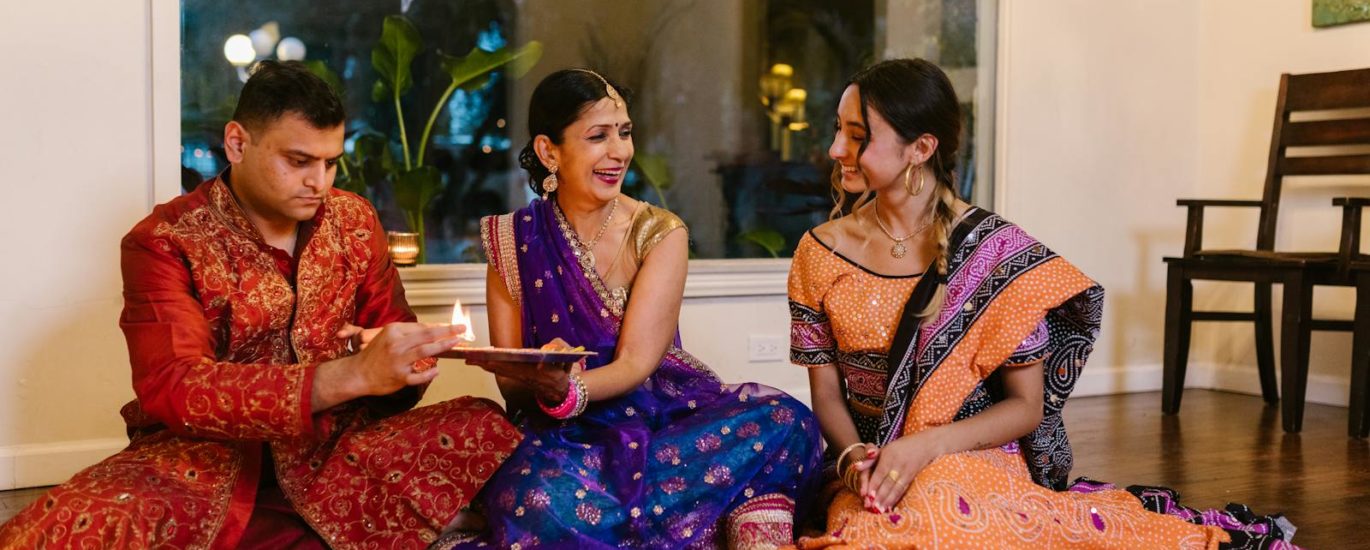 A joyful indoor gathering celebrating a traditional Indian ceremony with family members in colorful attire.