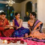 A joyful indoor gathering celebrating a traditional Indian ceremony with family members in colorful attire.