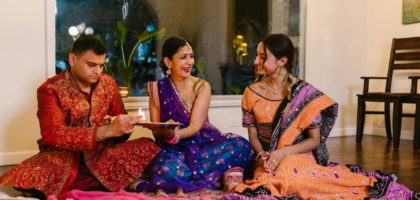 A joyful indoor gathering celebrating a traditional Indian ceremony with family members in colorful attire.