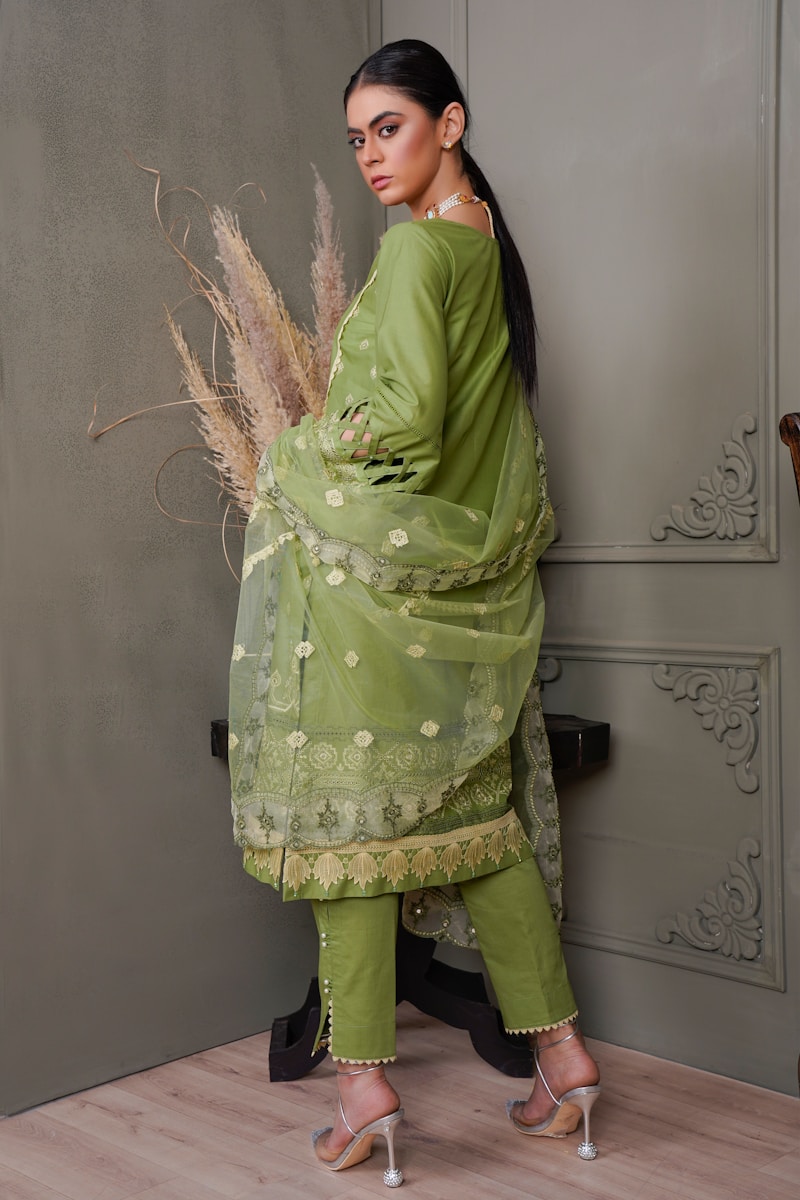 a woman in a green outfit standing next to a wall
