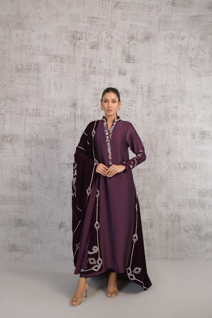 A woman in a purple dress standing in front of a wall