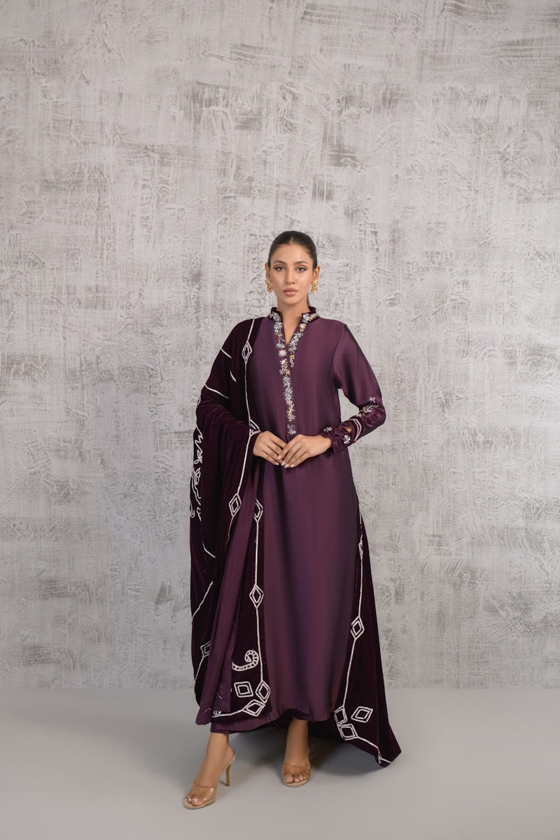 A woman in a purple dress standing in front of a wall