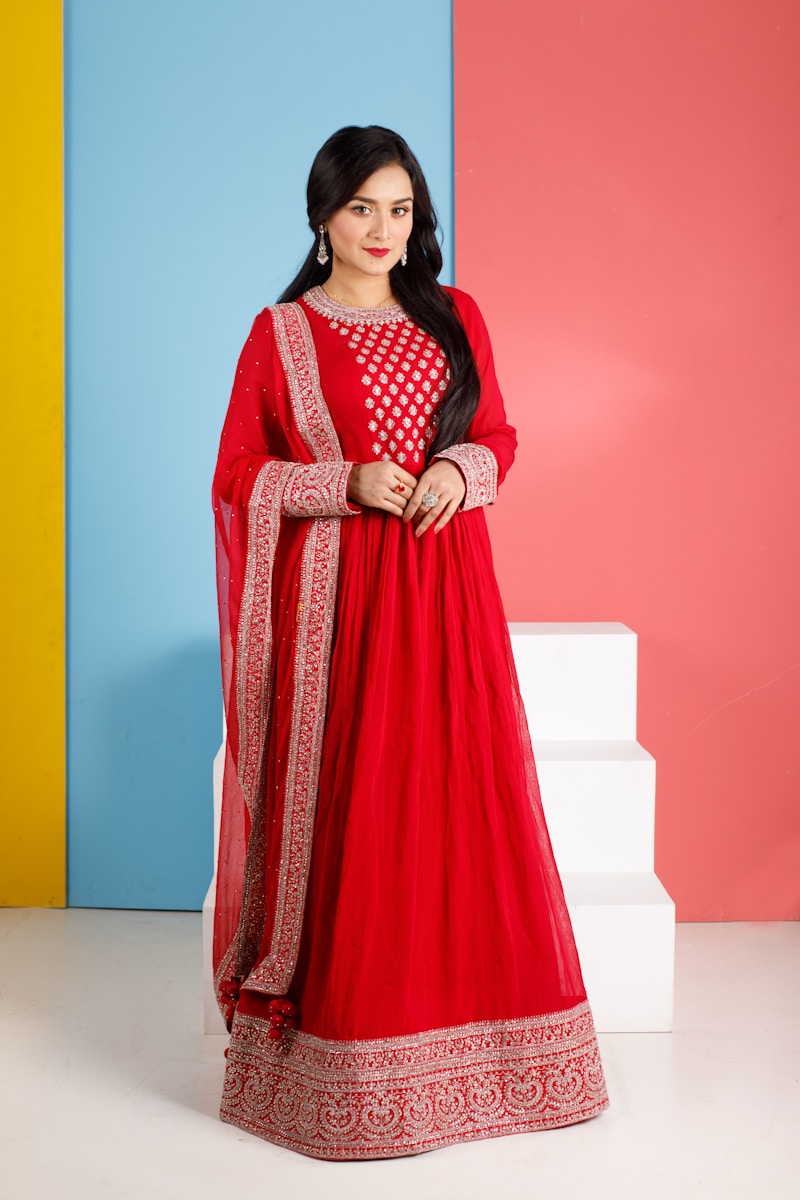 a woman in a red dress standing in front of a colorful wall