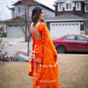 A woman in an orange dress standing in front of a house