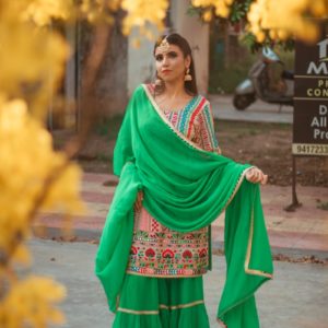 woman in green and red sari standing on gray asphalt road during daytime